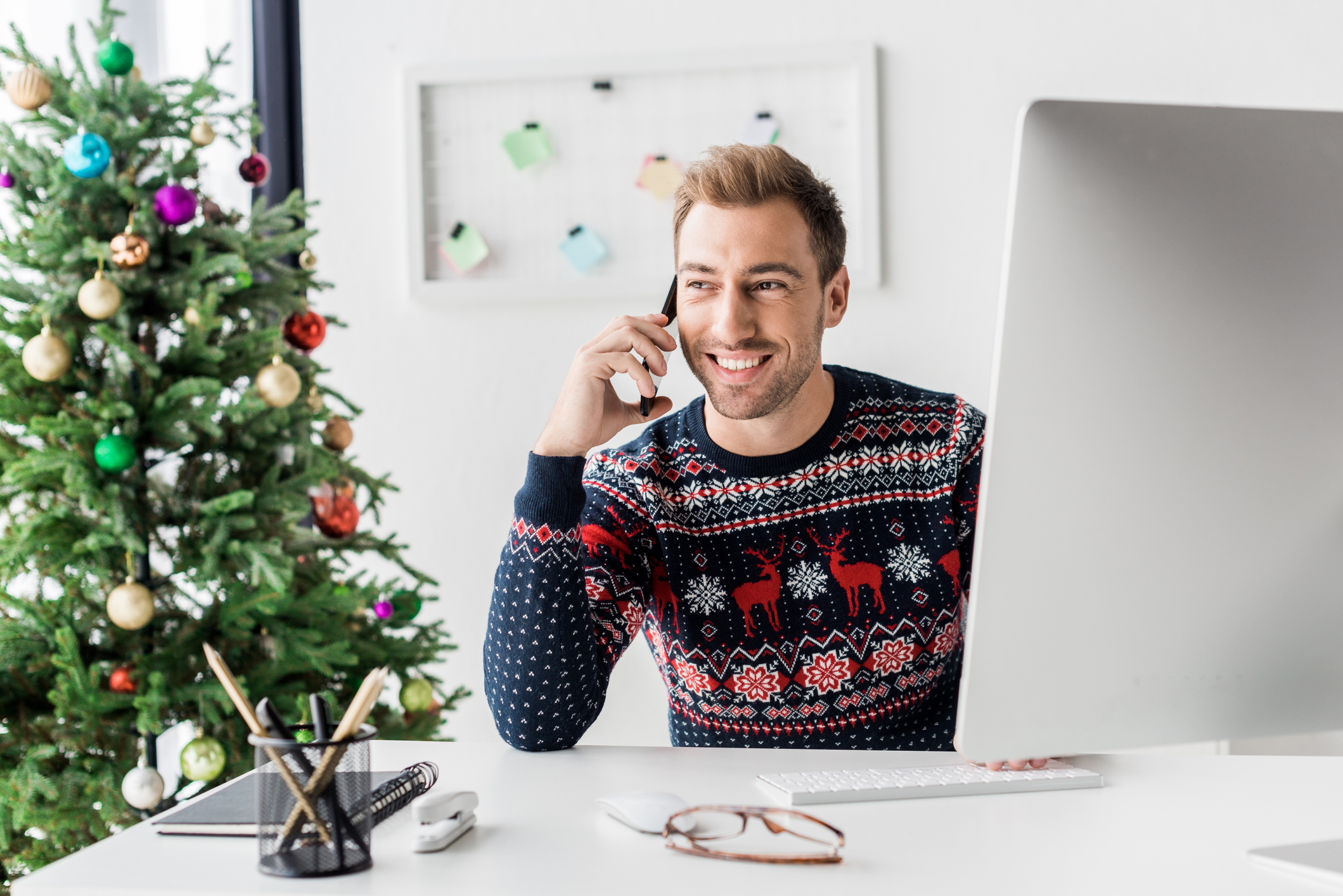 businessman in christmas sweater talking on smartphone in modern office insider risk management remote employee security